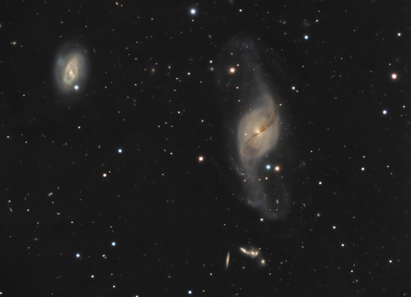 Im Bild sind zwei Galaxien zu sehen, links oben eine kleinere, rundliche und rechts neben der Mitte eine größere mit nach oben und unten herausgezogenen Spiralarmen.