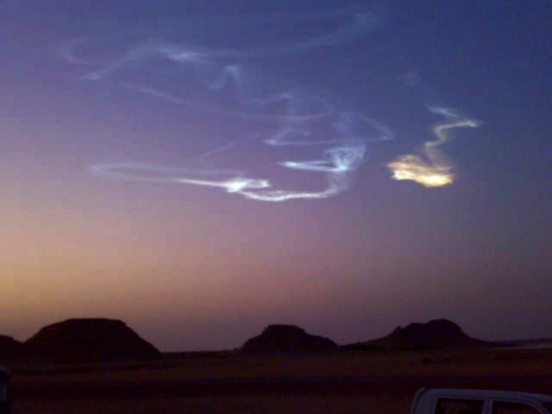 An einem klaren, violetten Abendhimmel nach Sonnenuntergang leuchten Wolkenschleier.