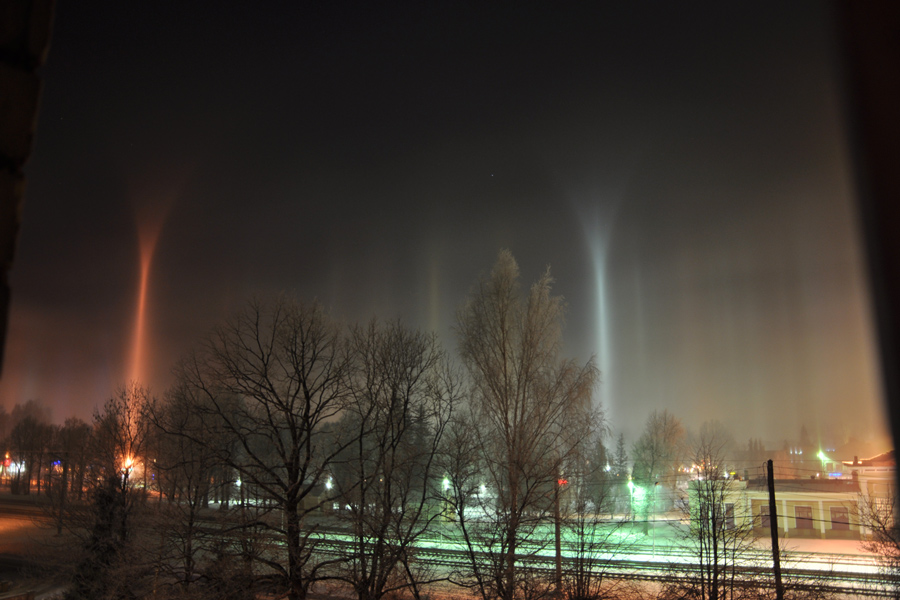 Über einer nebeligen Stadt reichen über Lampen Lichtsäulen aufwärts.