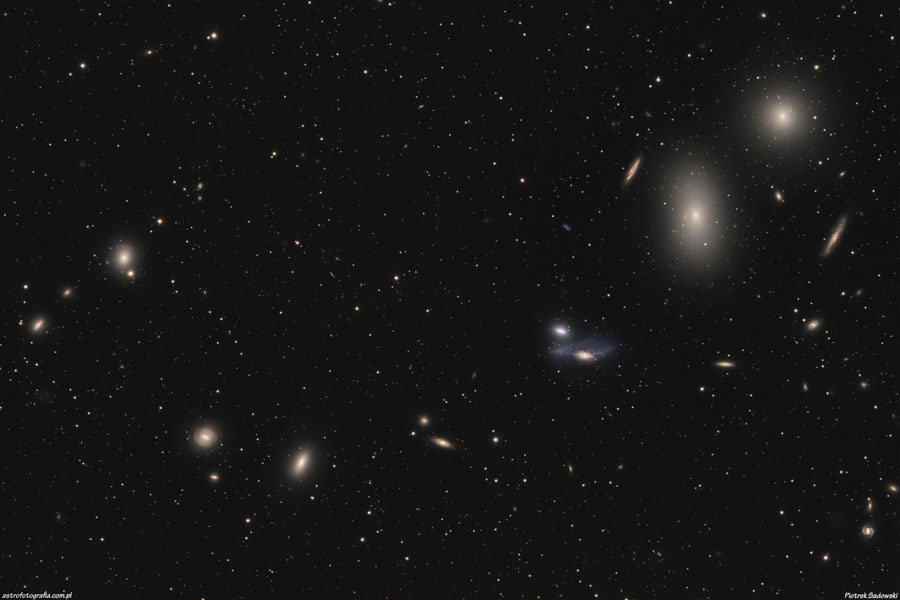 Durchs Bild verläuft eine kettenförmige Reihe Galaxien. Einige sind elliptische Galaxien, andere wirken verzerrt.