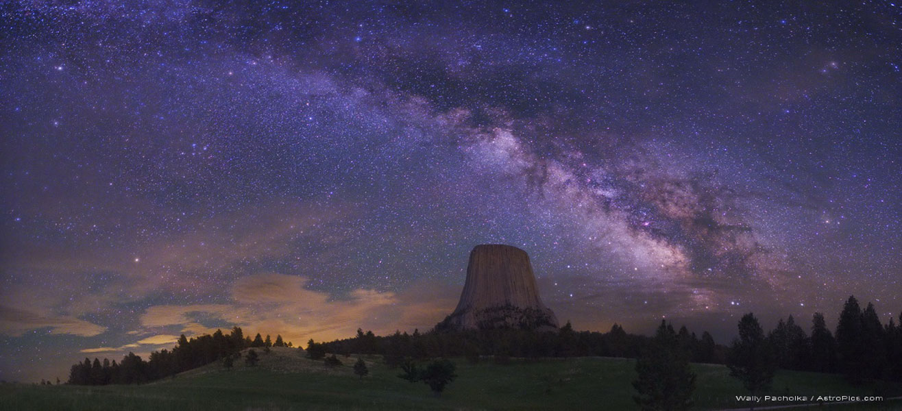 Auf dieser Nachtaufnahme steigt hinter der Silhouette des Teufelsturms in Wyoming am Horizont die Milchstraße nach links oben auf.