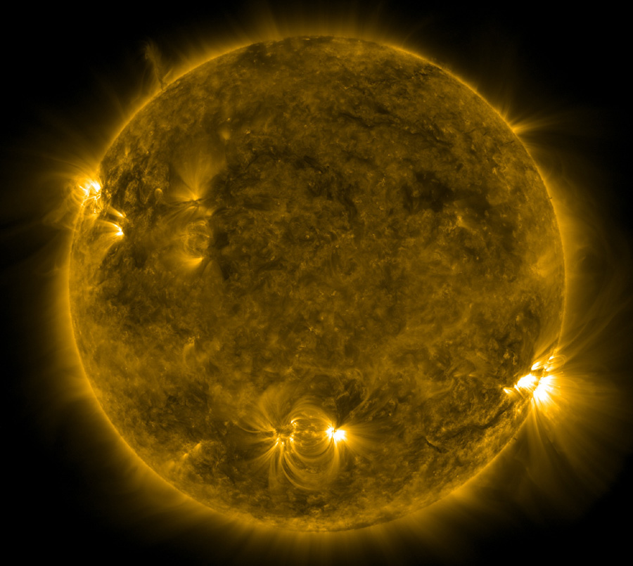 Die Sonne sieht auf diesem Bild ungewohnt dunkel aus, nur am Rand ist sie hell, und aus einigen Löchern strömen helle, büschelartige Lichter, unten sind zwei durch Schleifen miteinander verbunden.