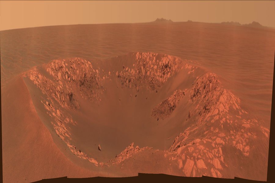 Mitten auf der roten Marsoberfläche, die bis zum Horizont reicht, ist ein Krater  mit hellroten Felsen am Rand abgebildet. Der Marshimmel hinten hat eine hellrote Farbe.
