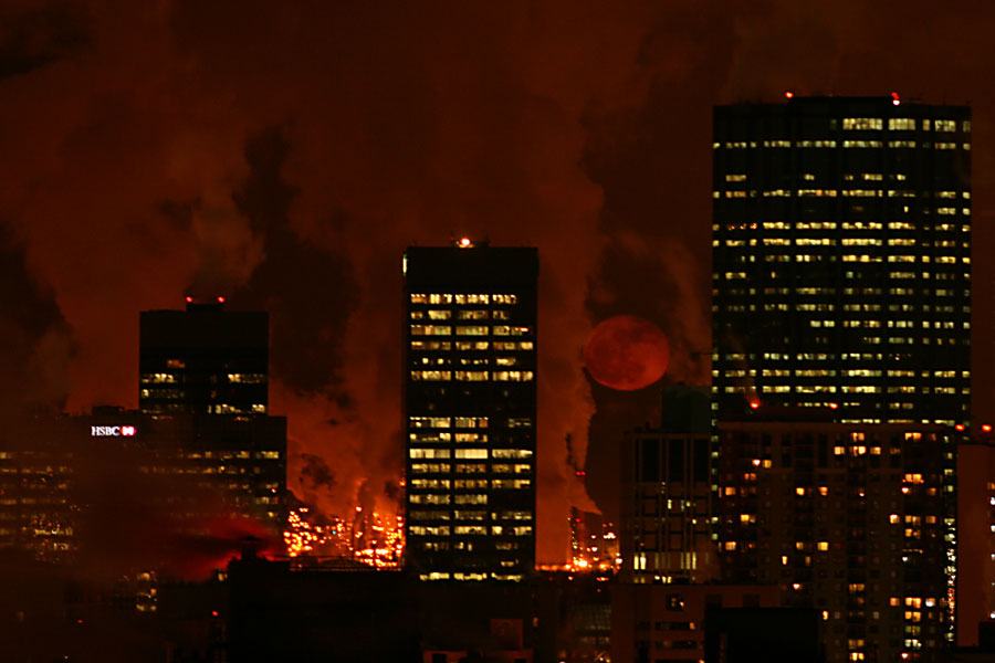 Hinter beleuchteten Wolkenkratzern steigen rote Schwaden auf, rechts hinten steigt der rote Mond auf.