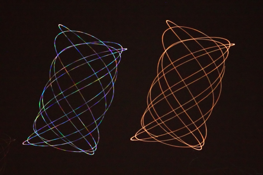 Zwei leuchtende Spuren wurden von einem schwingenden Teleskop gezogen. Links verläuft die Spur eines Sterns, diese schillert in allen Farben. Rechts leuchtet die orangefarbene Spur des Planeten Mars, der wegen seiner Fläche nicht flackert.