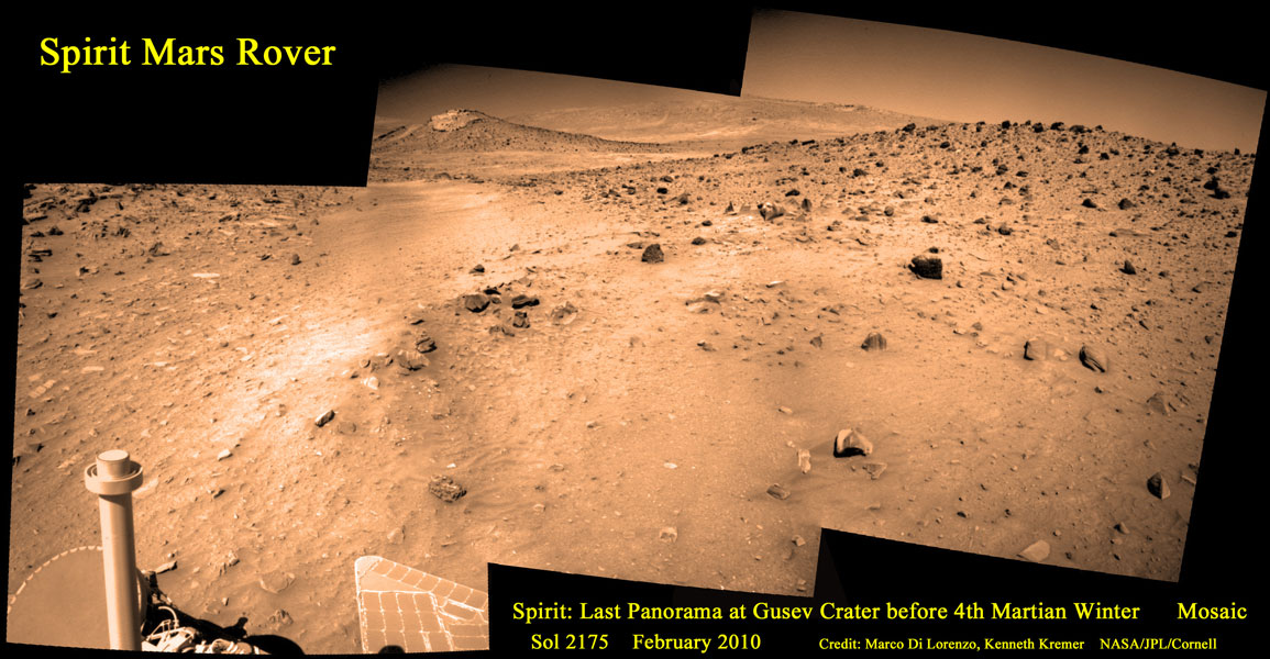 Das Bild wurde aus mehreren Aufnahmen zusammengesetzt. Links vorne ist ein Teil des Marsrovers Spirit zu sehen, dahinter eine rotbraune Geröllebene, die bis zum Horizont reicht.