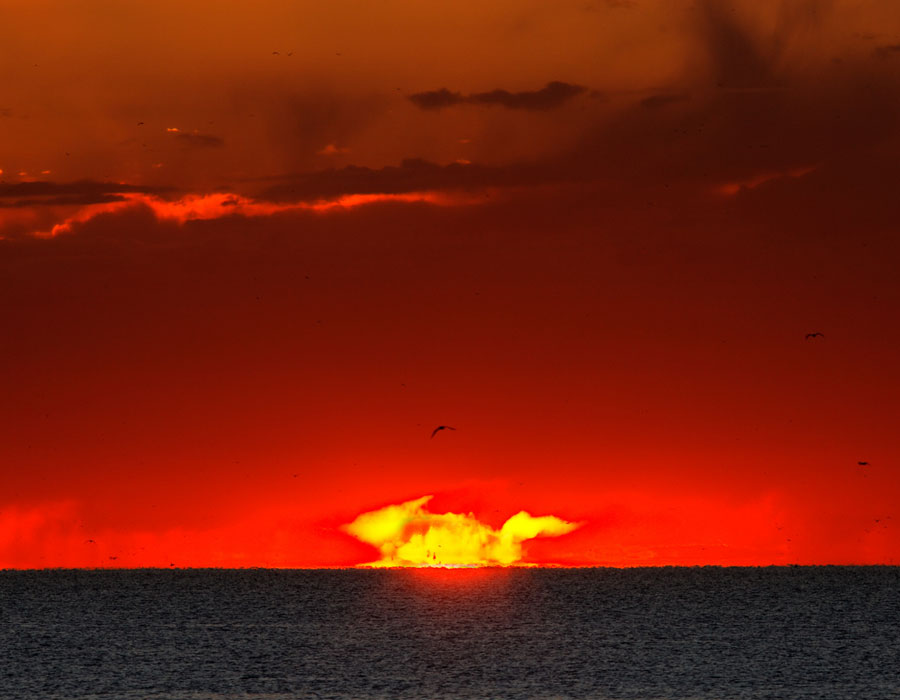 Über dem Rio de La Plata leuchtet ein seltsames Gebilde wie ein Feuer, es ist jedoch einfach nur die aufgehende Sonne, die verzerrt aussieht. Der Himmel ist rot gefärbt.