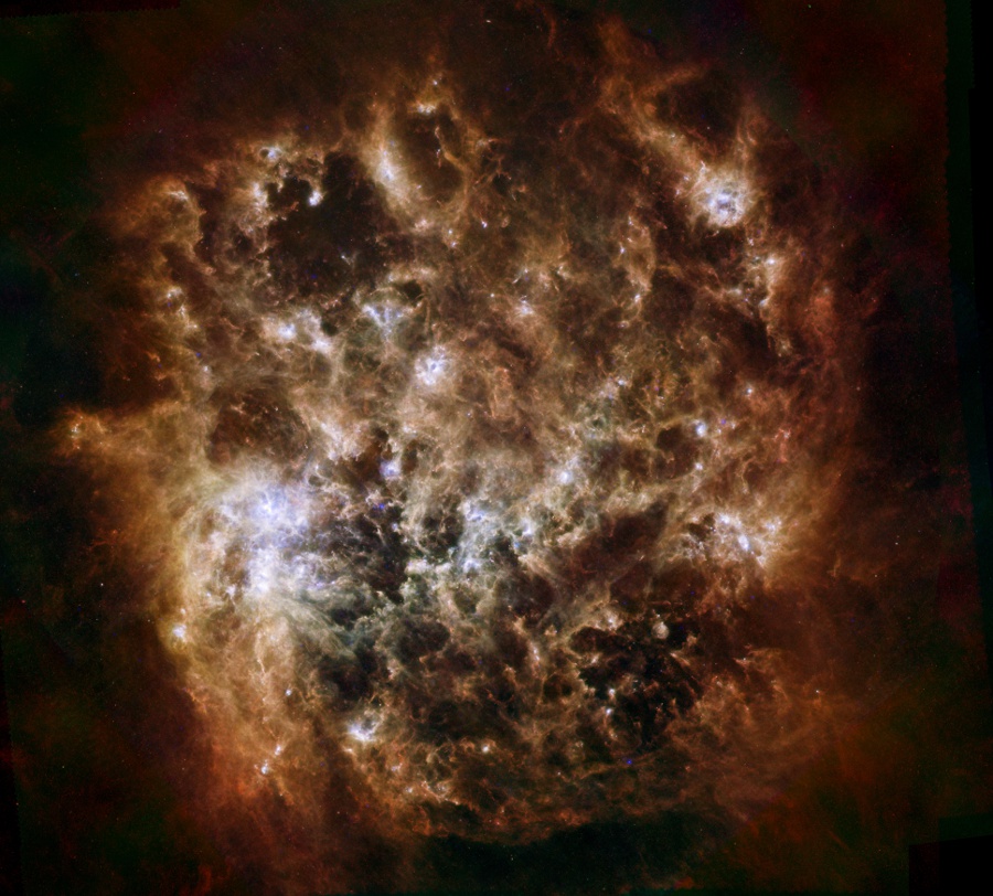Die verworrenen Staubwolken im Bild wurden vom Infrarotteleskop Herschel aufgenommen. Sie leuchten bräunlich mit einigen weißen Glanzlichtern.