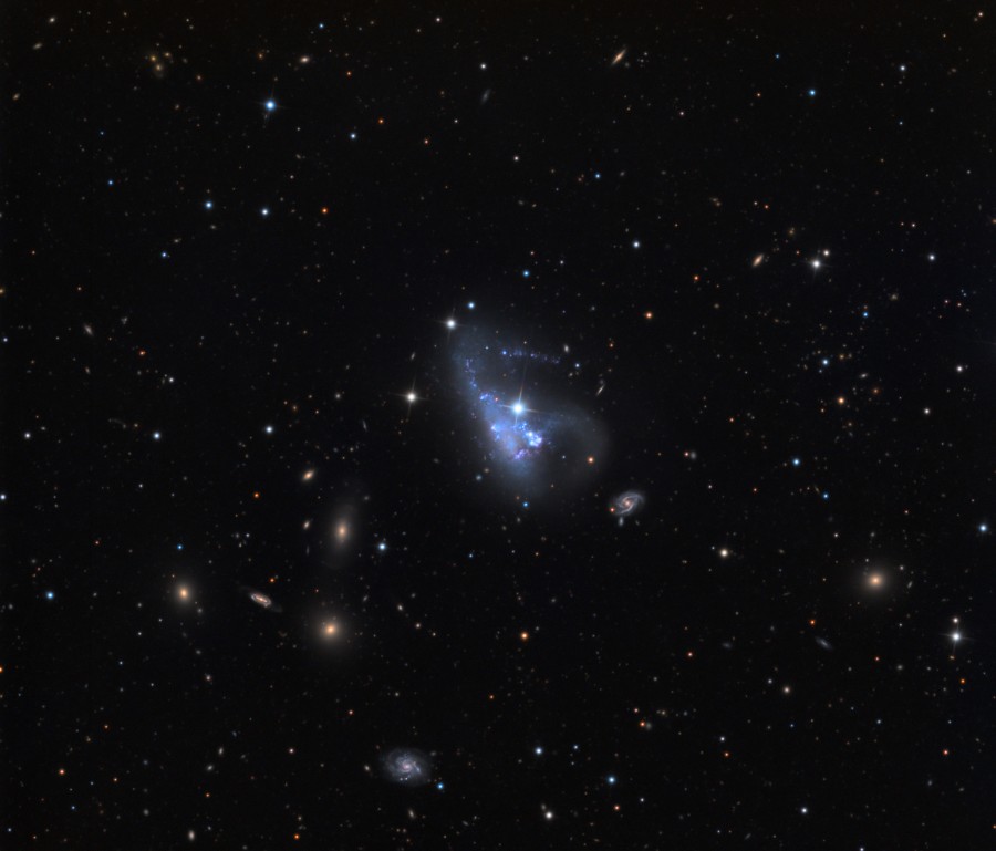 Mitten im Bild ist eine kleine, blau leuchtende Zwerggalaxie, die irregulär geformt ist. Der Stern an ihrem rechten oberen Ende gehört nicht dazu, er liegt in unserer Milchstraße.