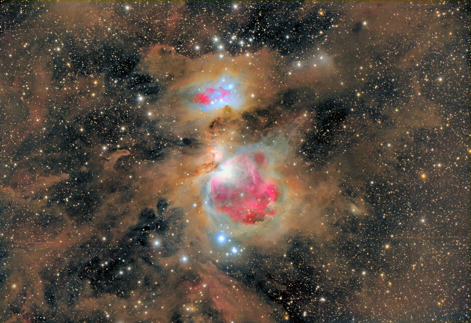 Der Orionnebel im Bild ist von üppigen braunen Staubwolken umgeben. Im Bild sind auch ziemlich gleichmäßig Sterne verteilt.
