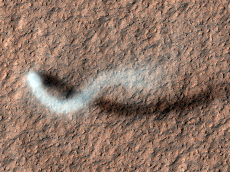 Über einer rötlichen, felsigen Marslandschaft ist ein weißer Staubwirbel, der einen dunklen Schatten wirft.