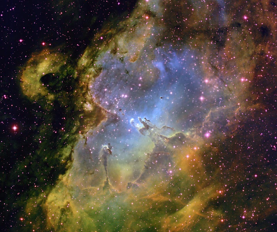 Wir blicken in M16 im Sternbild Schlange, eine Höhlung in einer Molekülwolke, deren Inneres blau beleuchtet ist. In der Mitte der Höhle ragen die berühmten Säulen der Sternbildung auf. Links ist ein weiterer markanter Dunkelnebel, die Fee des Adlernebels.
