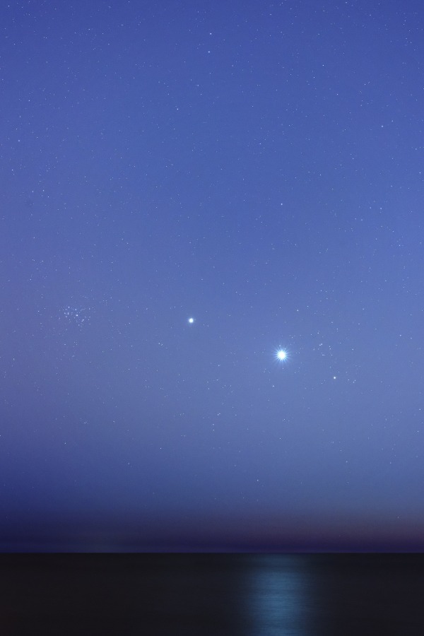Die Planeten Venus und Jupiter begegnen dem Sternhaufen der Plejaden. Auch der Asteroid Vesta und der Kleinplanet Ceres sind im Bild. Die Aussicht bei Buenos Aires in Argentinien reicht hinaus übers Meer.