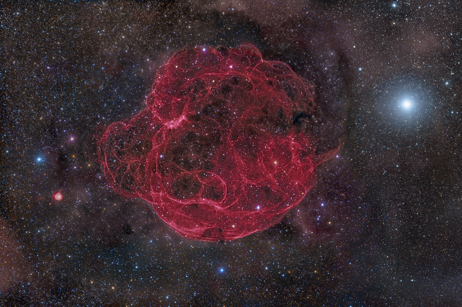 Das Bild zeigt den rot leuchtenden Supernovaüberrest Simeis 147, der wegen seiner Form, die scheinbar aus verschlungenen Fasern besteht, auch Spaghettinebel genannt wird.