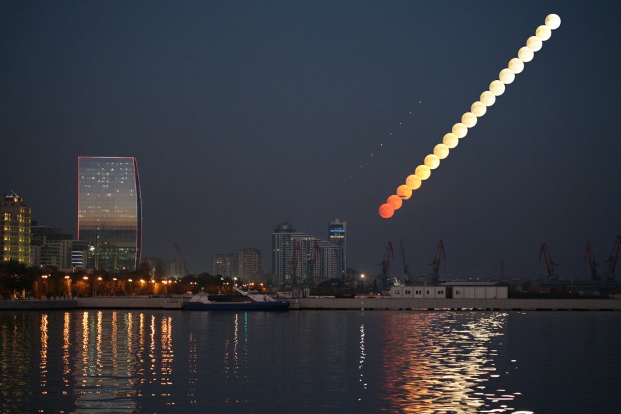 Über dem Hafen von Baku am Kaspischen Meer in Aserbaidschan geht der Vollmond auf. Er war während einer Halbschattenmondfinsternis leicht abgedunkelt.