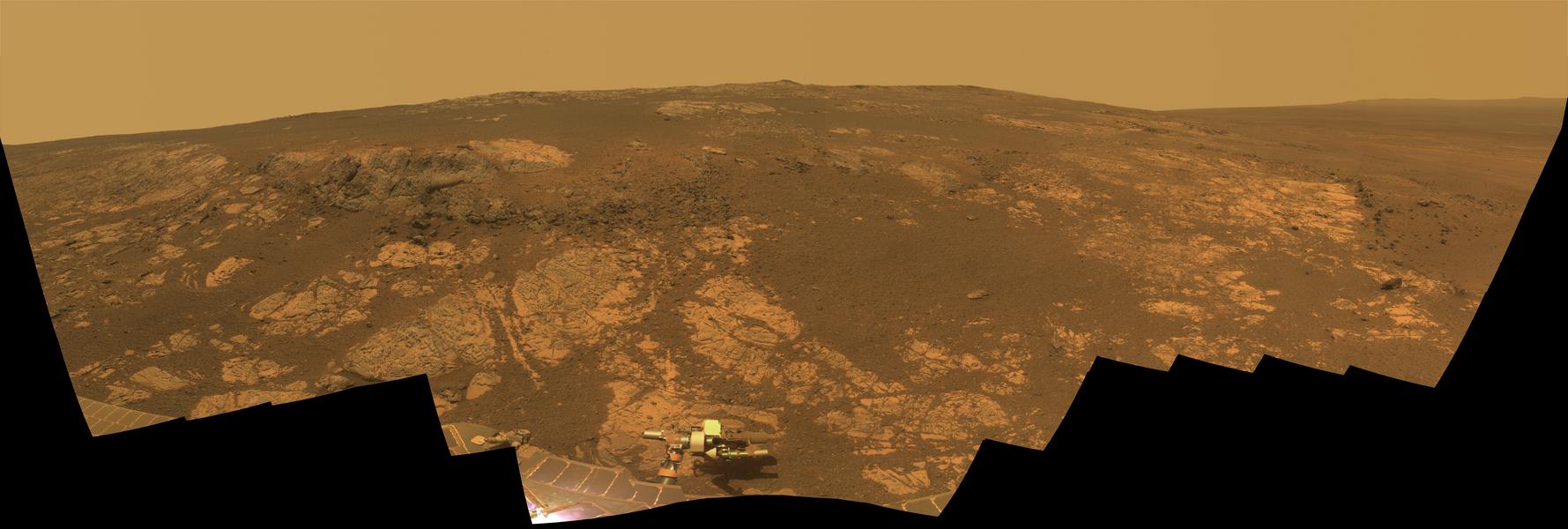 Das Mosaik aus Bildern des Marsrovers Opportunity zeigt eine felsige Landschaft, links ist ein dunkler Ausbruch, rechts eine Stelle mit hellem Gestein. Vorne ragen Teile des Rovers ins Bild.