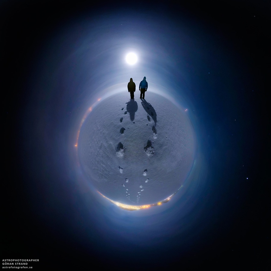Über einem nebeligen kleinen Planeten leuchtet der helle Vollmond. Zwei riesige silhouettenhafte Gestalten zogen Spuren im Schnee auf dem kleinen Planeten, der hier abgebildet ist.