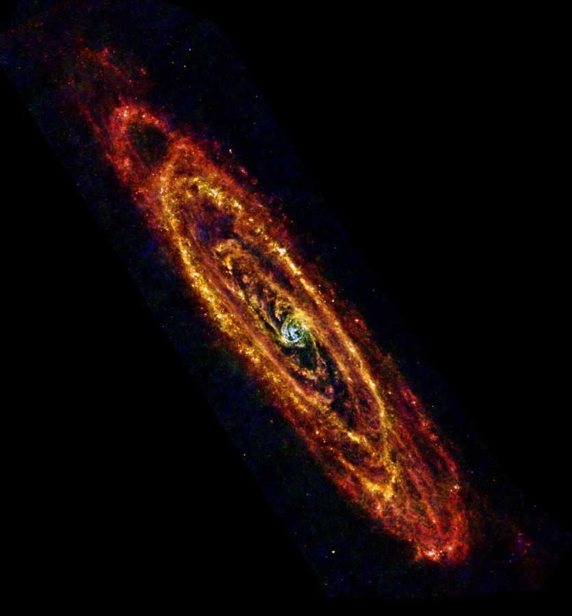 Die Galaxie im Bild wirkt fremdartig, weil nicht ihre Sterne gezeigt werden, sondern der Staub, der normalerweise dunkel ist. Um einen Kern verlaufen gewundene, orangefarben und gelb leuchtende Ranken.