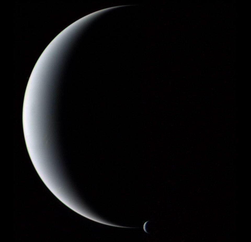 Der Planet Neptun ist hier als Sichel zu sehen, am unteren Ende ist die Sichel seines Mondes Triton.