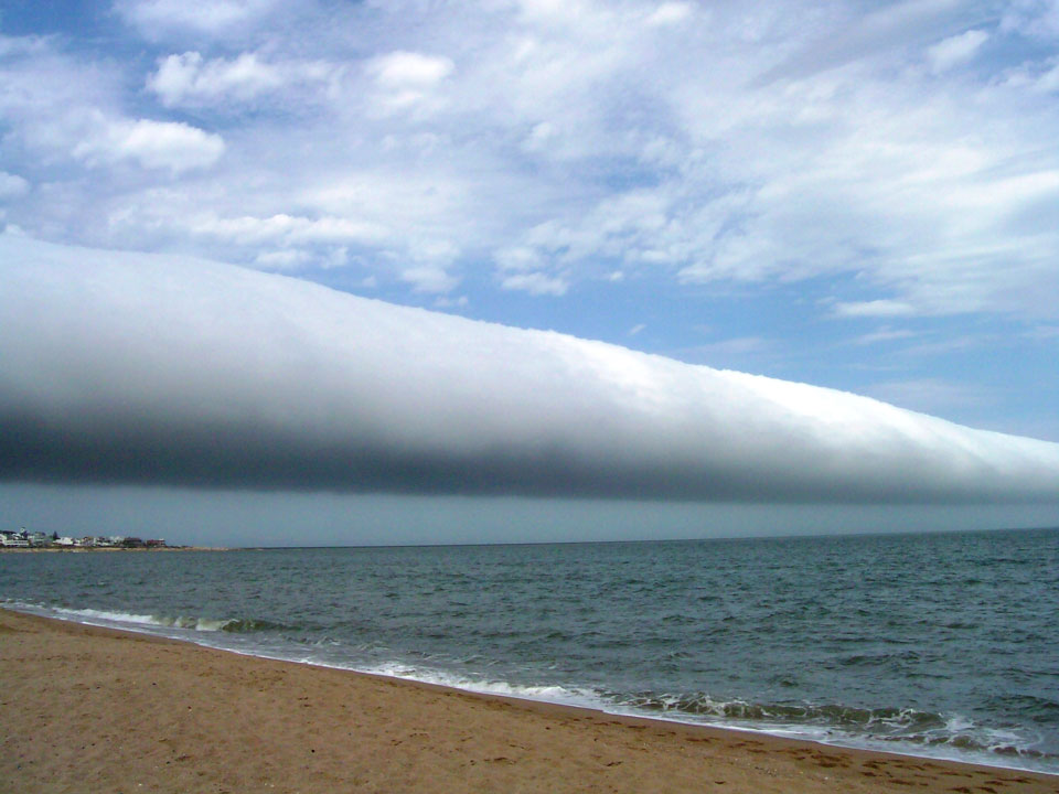 Von einem Strand aus rollt eine riesige Böenwalze über das Meer.