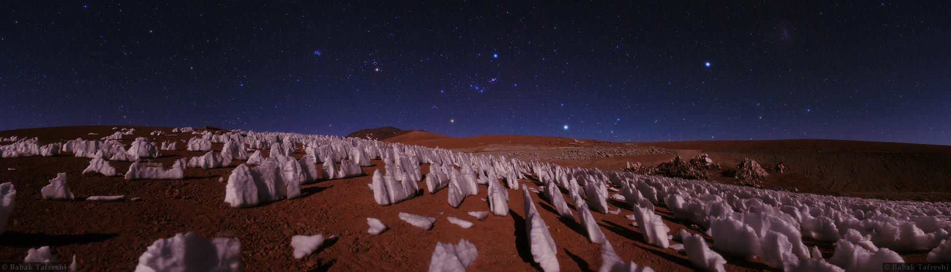 Auf einer Hochebene sind Eisspitzen auf einem braunen Boden verteilt. Sie werden von Mondlicht beleuchtet. Darüber breitet sich ein prachtvoller Sternenhimmel aus.