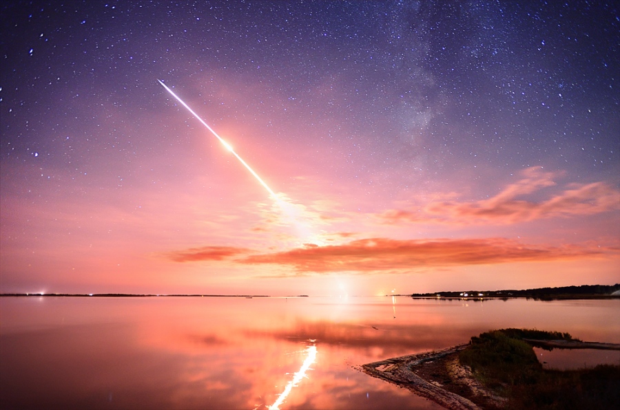 Eine MinotaurV-Rakete startet an der Wallops-Startanlage in Virginia ins All, sie transportiert die Raumsonde LADEE. Die Leuchtspur spiegelt sich im ruhigen Wasser.
