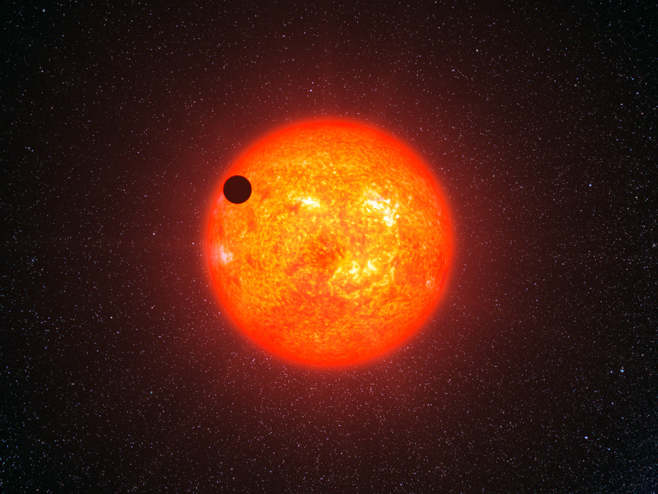 Vor einem rot-orangefarben leuchtenden Stern mit starker Struktur ist ein schwarzer Kreis. Das Bild ist eine Illustration, es zeigt die Supererde Gliese 121 4b vor ihrem Heimatstern.
