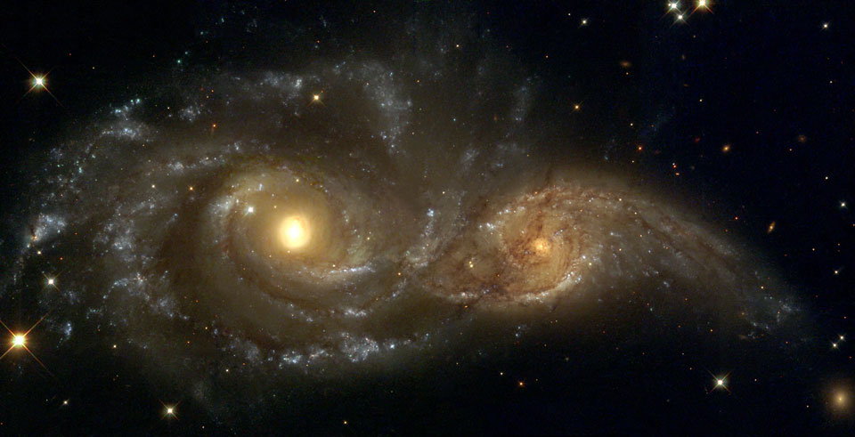 Die beiden gelb leuchtenden Spiralgalaxien im Bild erinnern an Augen. Sie treten offensichtlich miteinander in Wechselwirkung.