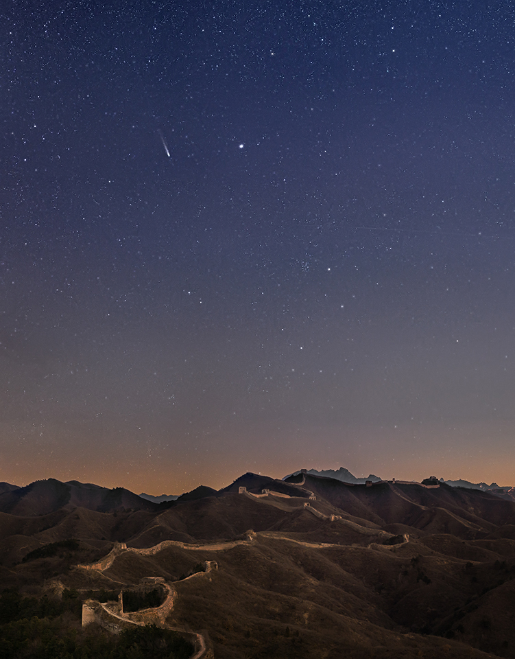 Auf einem Gebirge windet sich die Chinesische Mauer. Darüber leuchten am Himmel in der Dämmerung Komet Lovejoy und der Stern Ras Alhague im Schlangenträger.