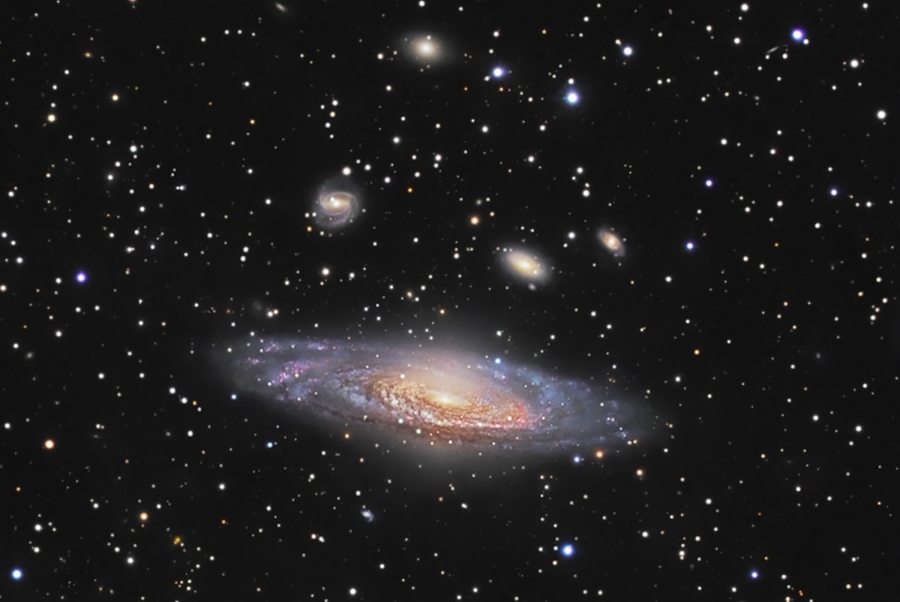 Vorne in der Mitte schwebt die seitlich sichtbare Spiralgalaxie NGC 7331. Sie wirkt am Rand etwas unscharf und insgesamt etwas verkrümmt. Darüber sind kleinere Galaxien verteilt, im Vordergrund leuchten viele Sterne in der Milchstraße. Das Bild hat eine seltsame Tiefenwirkung.