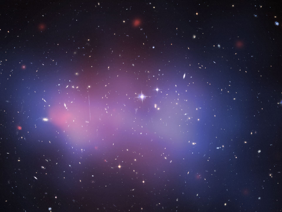 Der rosarote Nebel im Bild zeigt die Röntgenstrahlung eines der massereichsten Galaxienhaufen, die wir kennen. Der blaue Nebel im Bild zeigt die berechnete Verteilung der Dunklen Materie, sie wurde anhand der Verzerrung dahinter liegender Galaxien berechnet.