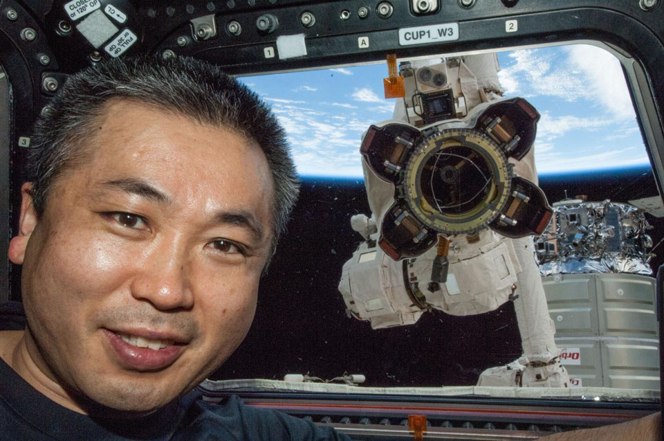 Hinter dem japanischen Stationskommandanten Koichi Wakata klopft der Roboter AFJ013 ans Fenster der Cupola. Er ist am Canadarm2 befestigt.