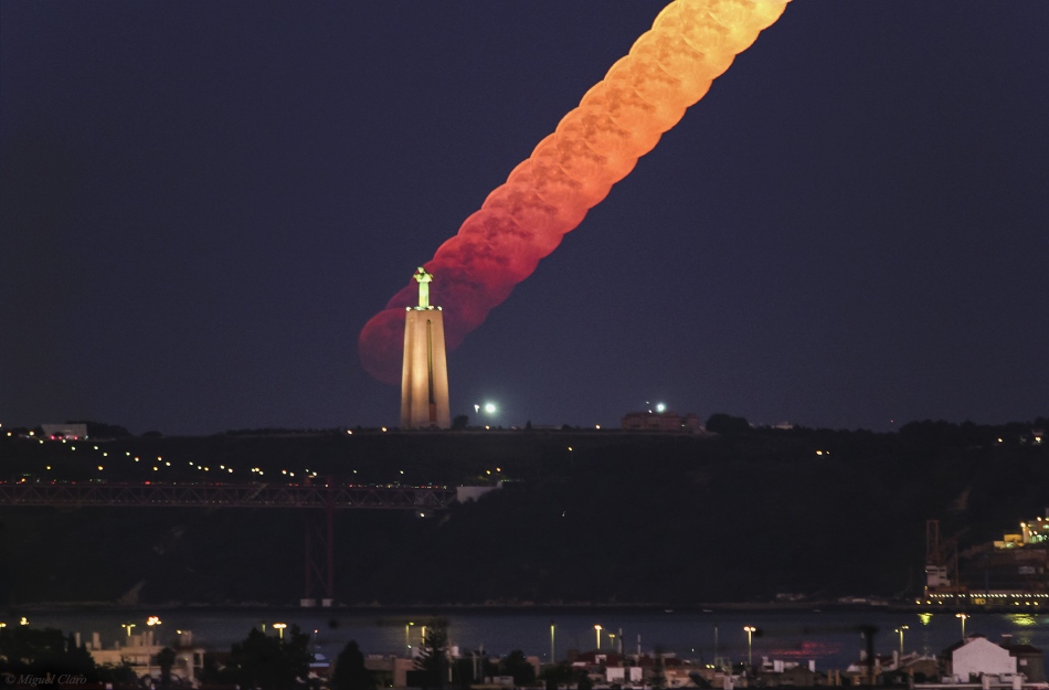 Am Horizont steht die Cristo-Rei-Statue über Lissabon. Dahinter geht der Mond auf. Am Horizont ist er noch dunkelrot und kaum zu sehen. Je höher er steigt, desto heller und gelblicher wird er.