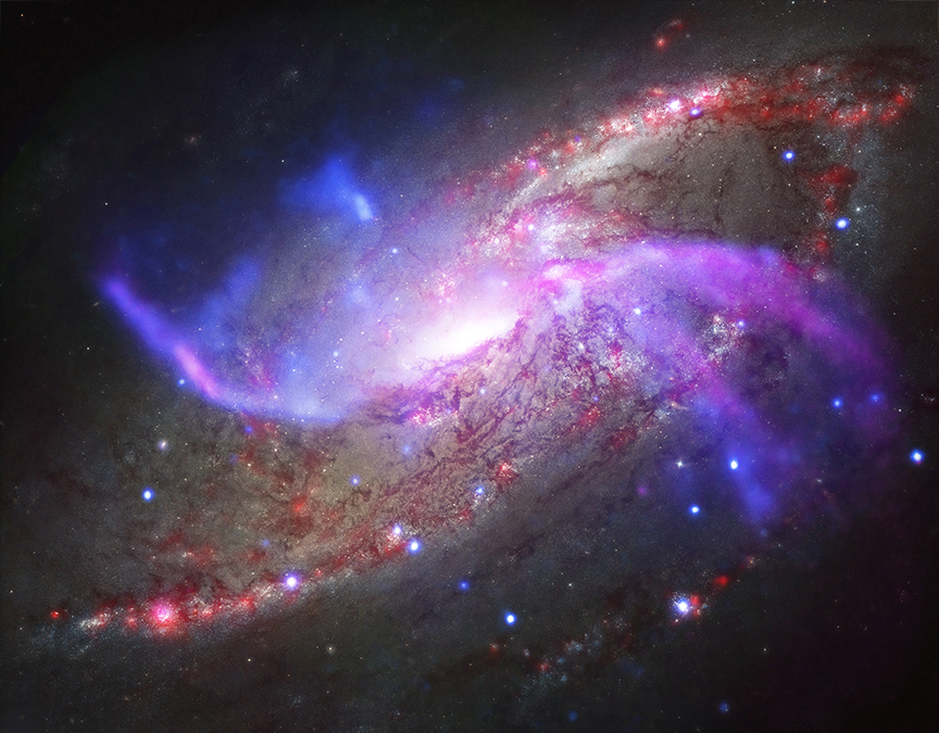 Aus einer Spiralgalaxie mit Staubbahnen und rötlichen Sternbildungsgebieten ragen violette Arme, die sich über die Galaxienscheibe erheben. Sie sind auf Bildern in sichtbarem Licht nicht zu sehen.