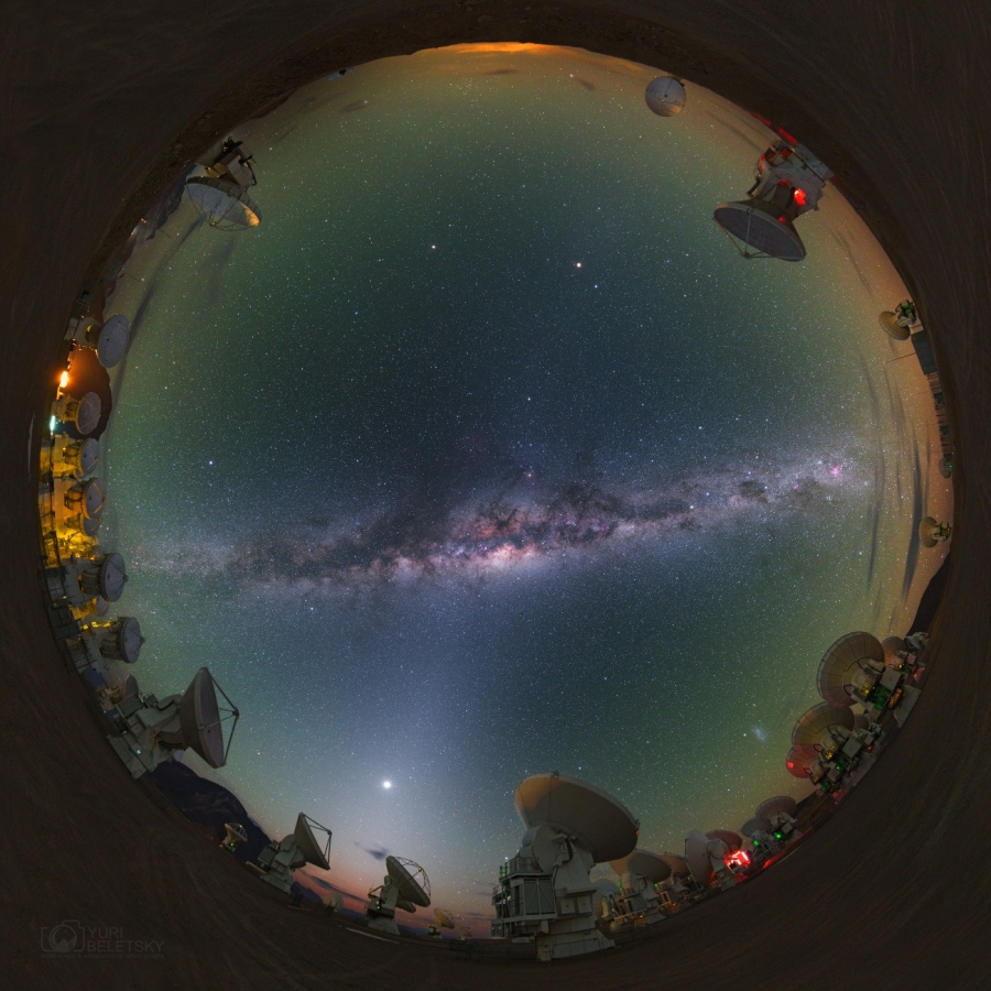 Das Bild zeigt den ganzen Himmel über der Chajantor-Hochebene in den chilenischen Anden. Quer über den Himmel verläuft die Milchstraße. Links unten strahlt die Venus im Zodiakallicht. Am Rand des kreisförmigen Horizonts sind die Teleskope von ALMA verteilt.
