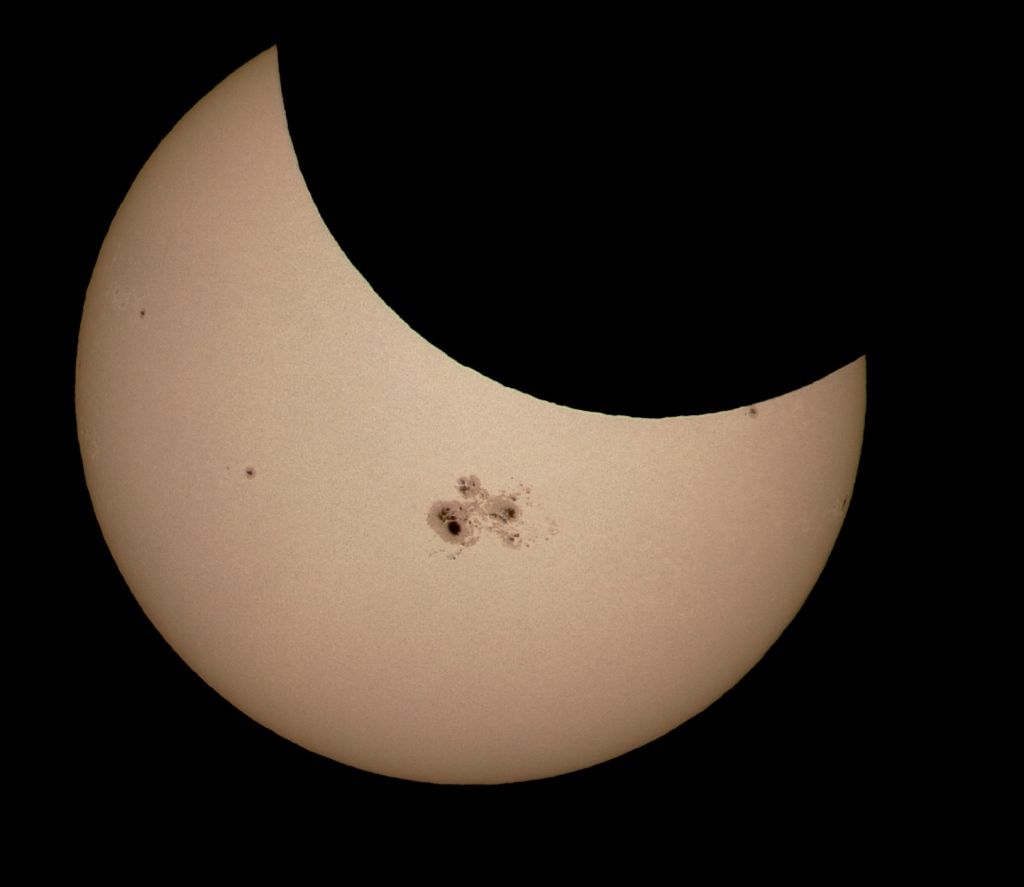 Die Sonne wird teilweise vom Neumond verdeckt. Mitten auf der Vorderseite ist die riesige Sonnenfleckengruppe AR 2192.