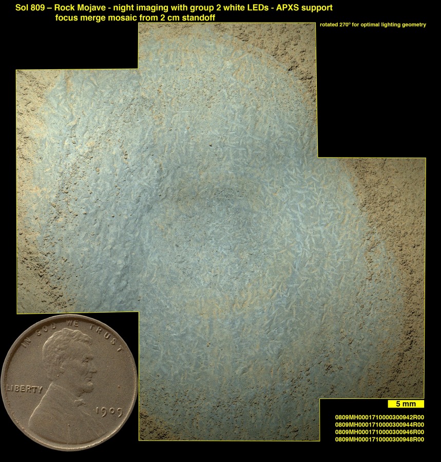 Die Nahaufnahme entstand mit dem Instrument MAHLI des Rovers Curiosity. Es zeigt längliche Formen, vermutlich Kristallstrukturen. Links unten ist ein 1909-Lincoln-Cent eingeblendet.