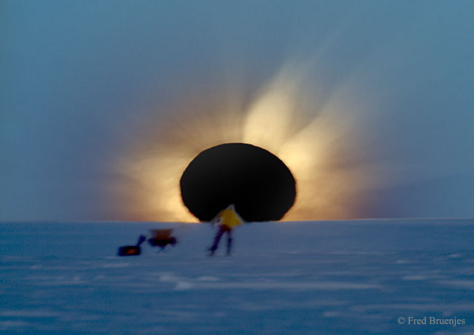 Am Horizont ist ein dunkler Kreis, umgeben von Feuerzungen, davor ist eine Gestalt. Bei einer totalen Sonnenfinsternis bedeckt der Mond die Sonne. Vorne stand ein Fotograf und prüfte seine Kamera.
