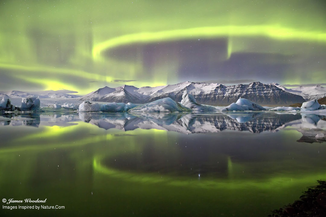 Über einem isländischen Gletscher schimmern grüne Polarlichter. Die Gletscherlagune vorne war so ruhig, dass sie die Sternbilder Schwan, Leier und Herkules spiegelte.