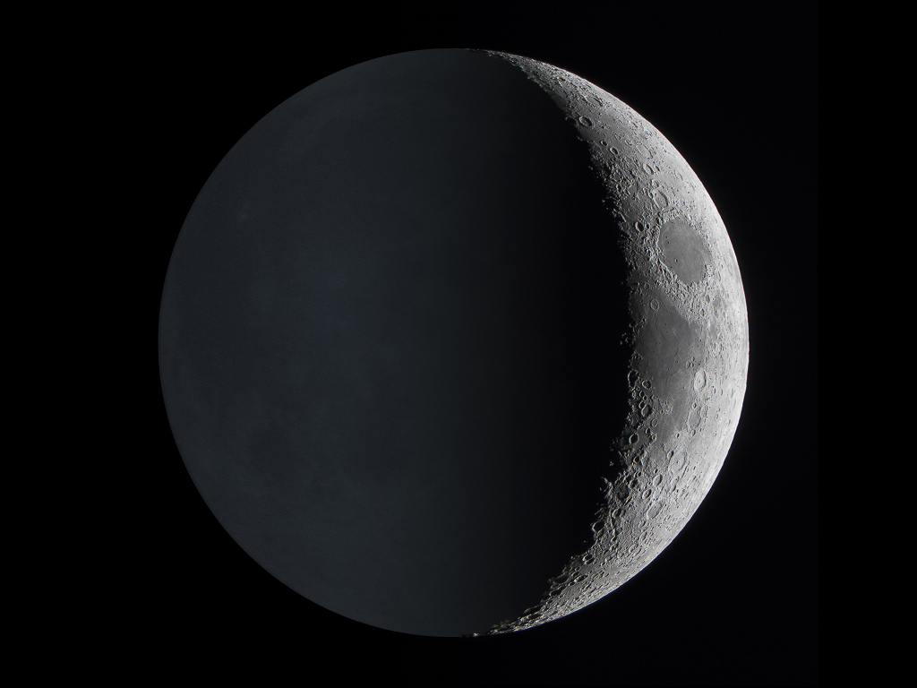 Links ist auf dem Mond Nacht. Trotzdem sieht man einige Details, weil die Erde die dunkle Seite des Mondes beleuchtet. Rechts erkennt man Krater und Lavabecken.