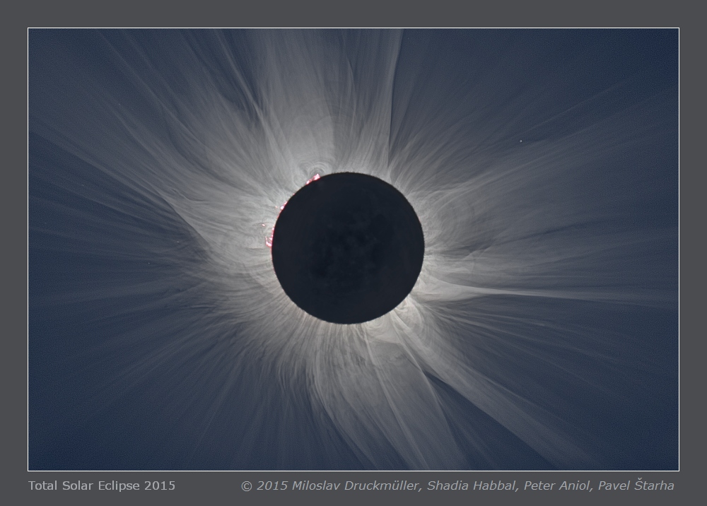 Um den dunklen Mond strömt die Sonnenkorona in langen Strahlen. Protuberanzen ragen über den Rand. Auf der Nachtseite des Mondes sind einige Details der Oberfläche erkennbar. Der Vollmond wird von der Vollerde beleuchtet, daher ist es auf der erdzugewandten Seite nie ganz dunkel.