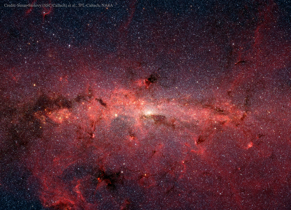 Das galaktische Zentrum wurde hier vom Weltraumteleskop Spitzer aufgenommen. Es beobachtet in Infrarot und kann daher durch die Staubwolken um das Zentrum Sgr A* hindurchblicken.