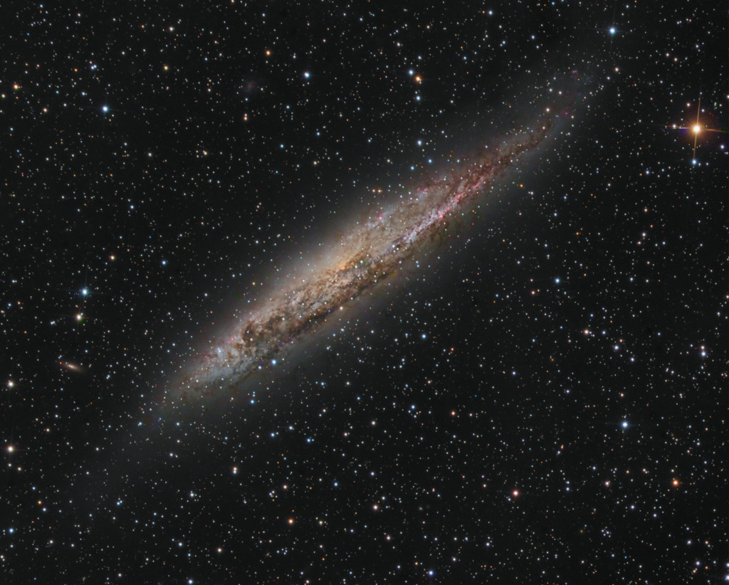 Schräg im Bild liegt eine Spiralgalaxie, die wir fast von der Seite sehen, mit Blick auf markante Staubbahnen. Die Seyfertgalaxie NGC 4945 liegt im Sternbild Zentaur.