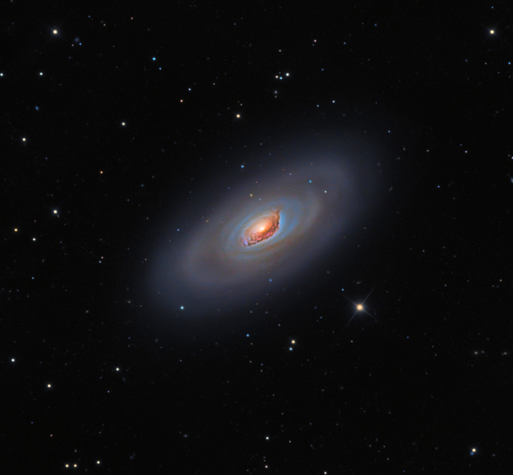 Die Galaxie M64 im Sternbild Haar der Berenike hat ein wildes Aussehen. Auf diesem Bild ist ein braunrötlich leuchtender Kern von blauen Schlieren umgeben, außen herum verlaufen diffuse spiralförmige Sternennebel.