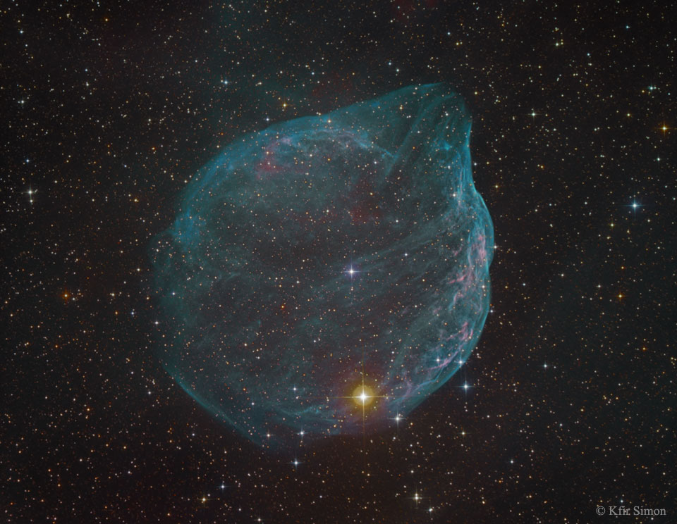 Der Nebel im Bild wirkt wie eine zarte Seifenblase. Sie leuchtet blau und ist von vielen kleinen Sternen umgeben. Das Gebilde wird von einem Wolf-Rayet-Stern aufgebläht.