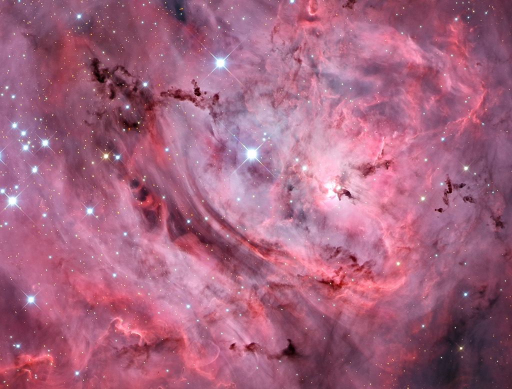 Klassik
Rot leuchtende Wolken füllen das Bild. Das Licht entsteht, wenn ionisierte Wasserstoffatome mit freien Elektronen rekombinieren. Dazwischen sind einige dunkle Wolkenstreifen und Sterne verteilt.
