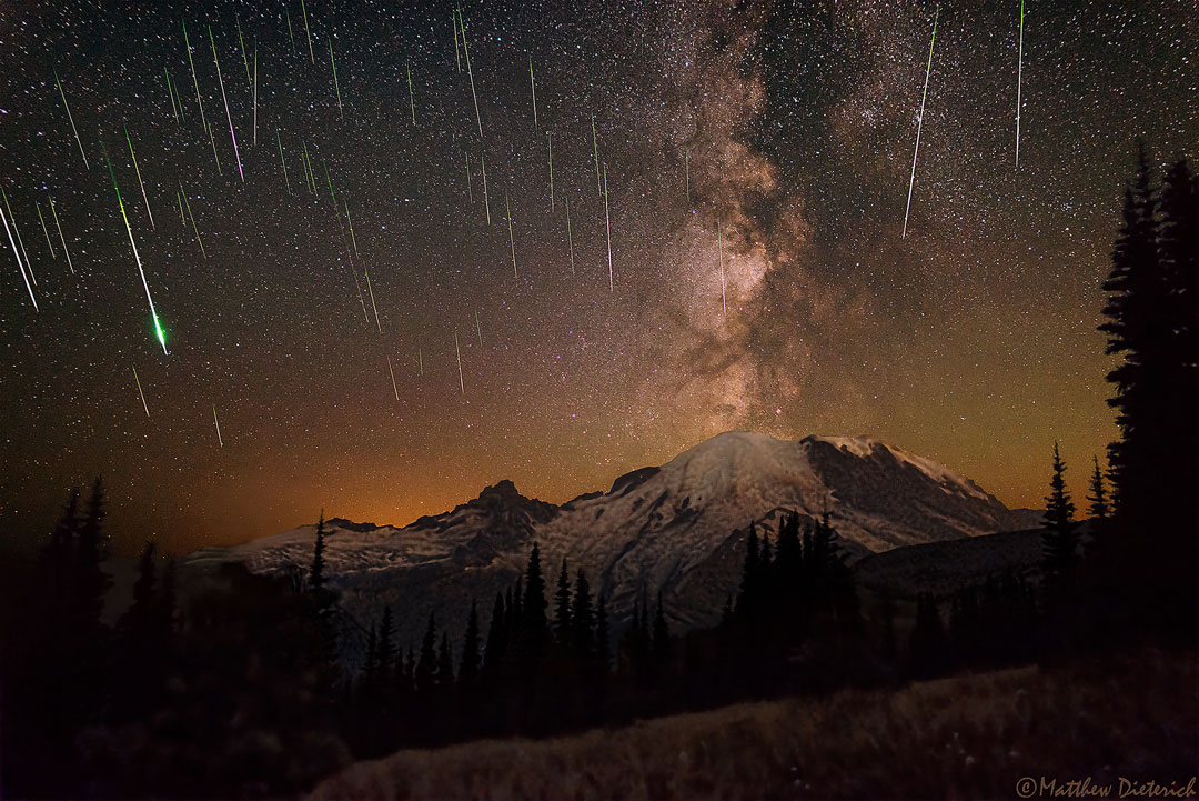Über dem Mount Rainier in Washington verläuft das Band der Milchstraße wie eine Aschewolke steil nach oben. Gleichzeitig fallen viele Meteore der Perseïden vom Himmel. Diese Kombination lässt das Bild sehr dramatisch wirken.