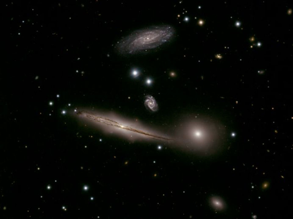 In dieser kompakten Hickson-Gruppe im Sternbild Steinbock umkreisen Galaxien ein gemeinsames Zentrum. Links sind zwei Spiralgalaxien, rechts unter der Mitte eine elliptische Galaxie. Die kleinen Galaxien sind wahrscheinlich viel weiter entfernt.