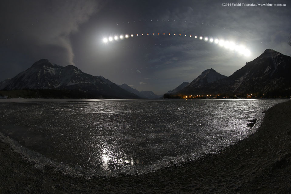 Hinter dem Waterton Lake und den Gipfeln des Glacier-Nationalparks wandert der Mond über den Himmel. In der Mitte taucht er in den Erdschatten ein. Mit dem Mond wandern auch Mars, Spica und Saturn über den Himmel.