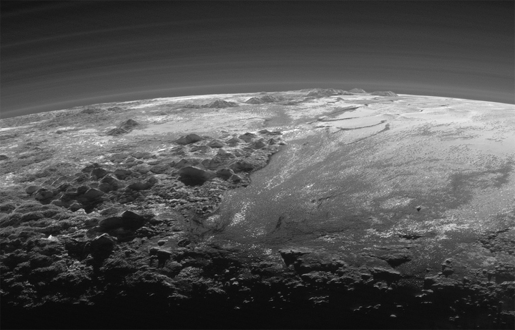 Die Raumsonde New Horizons nahm diese Ansicht nach ihrer größten Annäherung an Pluto auf. Sie zeigt zerklüftete Berge und eine glatte Ebene sowie Schichten einer dünnen Atmosphäre auf Pluto.